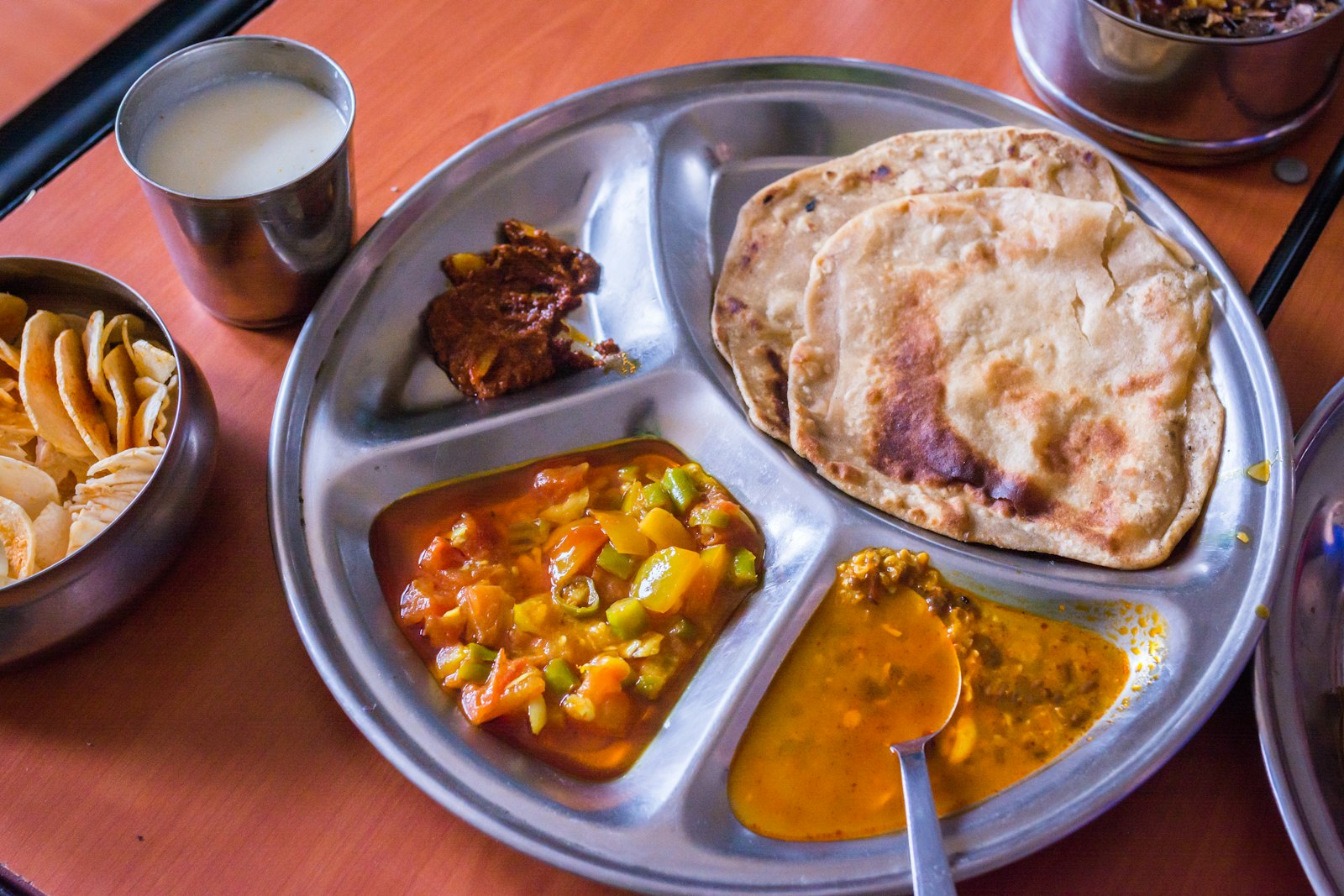 A Gujarati vegetarian thali with rotli, dal, kadhi, shaak, farsan and sweets